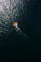 Top down aerial view of orange sailboat in water photo