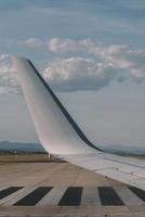 View from the porthole - Wing of an airplane taking off above the runway at high speed during the sunset. The land is running under the wing.. photo