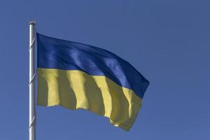 Ukrainian state flag on flagpole against blue sky photo