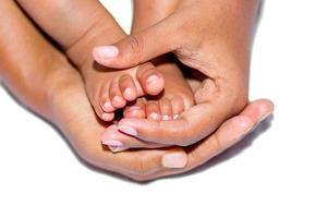 The soft legs of a baby placed on the palm of the mother's two hands on a white background. photo