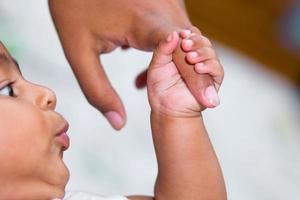 A asian baby's hand holding her mother finger photo