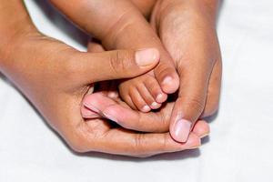 The soft legs of a baby placed on the palm of the mother's two hands on a white background. photo