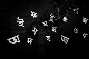el blanco letras de el bengalí alfabeto son siendo visible en el negro antecedentes. 21 febrero es el internacional madre idioma día de bangladesh foto