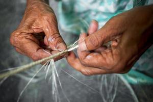 An old age woman is making on his skinny hands a rope from the banana tree fiber at Madhupur, Tangail, Bangladesh. photo