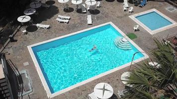 Aussicht von das oben wie ein Frau im ein Blau Badeanzug schwimmt im das Schwimmbad von ein Hotel, Villa oder Wohnung video