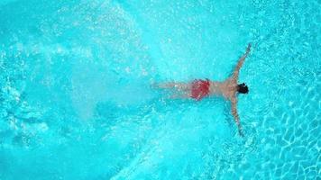 Aussicht von das oben wie ein Frau im ein Blau Badeanzug schwimmt im das Schwimmbad von ein Hotel, Villa oder Wohnung video