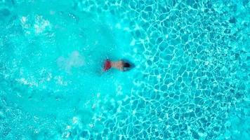 Aussicht von das oben wie ein Frau im ein Blau Badeanzug schwimmt im das Schwimmbad von ein Hotel, Villa oder Wohnung video