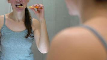 Pretty woman brushing her teeth in a bathroom in the morning. Morning hygiene. video