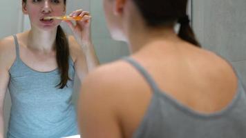 bonito mujer cepillado su dientes en un baño en el Mañana. Mañana higiene. video