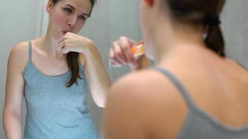bonita mulher escovar dela dentes dentro uma banheiro dentro a manhã. manhã higiene. video