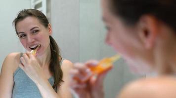 bonito mujer cepillado su dientes en un baño en el Mañana. Mañana higiene. video