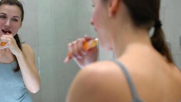 jolie femme brossage sa les dents dans une salle de bains dans le Matin. Matin hygiène. video