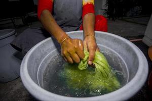 un mujer es limpieza en agua en manos con a mano el verde fibras hecho desde piña hoja. Respetuoso del medio ambiente productos agrícola residuos producto. foto