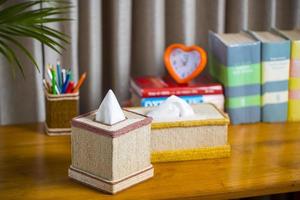 A tissue box on a wooden reading table. A tissue box made of fiber. Pineapple leaf fiber. photo