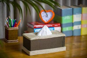 A tissue box on a wooden reading table. A tissue box made of fiber. Pineapple leaf fiber. photo