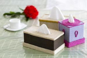 Handmade fiber Napkin boxes on the dining table with a red flower and a tea-cup. Tissue paper box on restaurant. photo