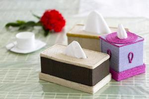 Handmade fiber Napkin boxes on the dining table with a red flower and a tea-cup. Tissue paper box on restaurant. photo