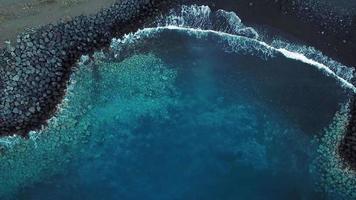 Haut vue de une déserté noir volcanique plage. côte de le île de tenerife. aérien drone métrage de mer vagues atteindre video