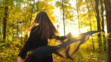 Beautiful girl holds the hand of her boyfriend and follows him through the yellow autumn forest. Slow motion video