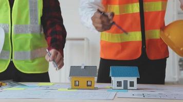 costruzione e struttura concetto di ingegnere o architetto incontro per progetto Lavorando con compagno e ingegneria utensili su modello edificio e planimetria nel Lavorando luogo, contrarre per tutti e due aziende. video