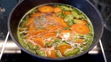 Koken werkwijze van koken broccoli en wortels net zo een eetpatroon maaltijd in een elektrisch fornuis met een marmeren pan. video