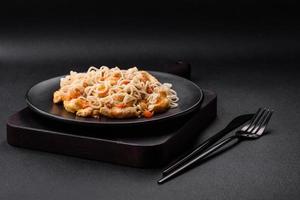 Delicious noodles with chicken and vegetables or udon on a black ceramic plate photo