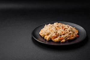delicioso tallarines con pollo y vegetales o udon en un negro cerámico plato foto