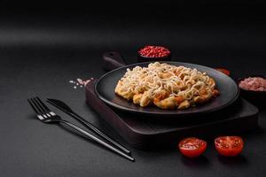 delicioso tallarines con pollo y vegetales o udon en un negro cerámico plato foto