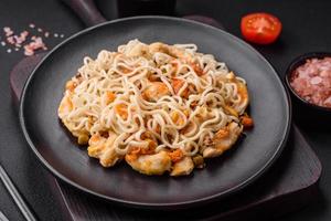 delicioso tallarines con pollo y vegetales o udon en un negro cerámico plato foto