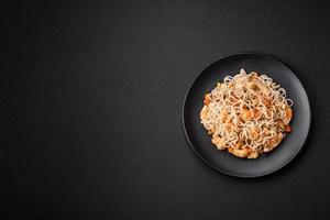 Delicious noodles with chicken and vegetables or udon on a black ceramic plate photo