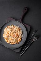 delicioso tallarines con pollo y vegetales o udon en un negro cerámico plato foto