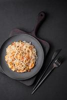 Delicious noodles with chicken and vegetables or udon on a black ceramic plate photo