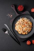 Delicious noodles with chicken and vegetables or udon on a black ceramic plate photo