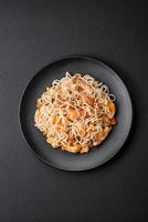 Delicious noodles with chicken and vegetables or udon on a black ceramic plate photo