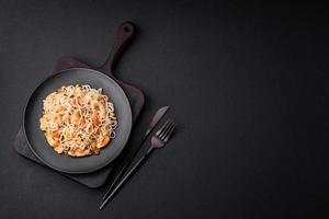 Delicious noodles with chicken and vegetables or udon on a black ceramic plate photo