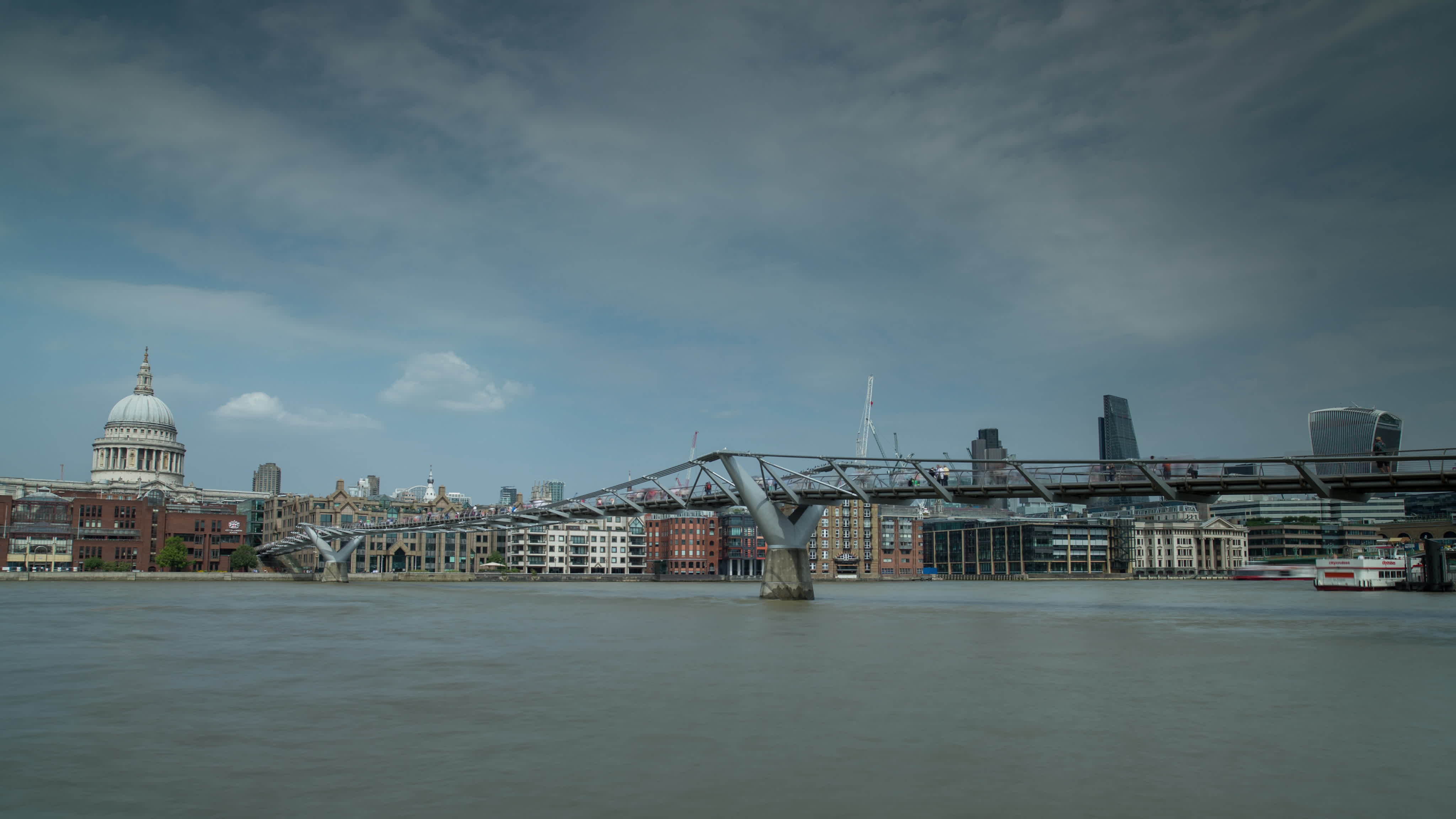 timelapse of the London skyline and people crossing the millennium