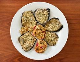 Gratinated pepper in a white dish on wooden table. Top view photo