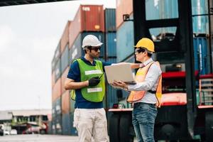 Team Engineer and worker wear safety uniform check control loading freight cargo container use computer laptop at commercial dock warehouse,transportation import,export logistic industrial service photo