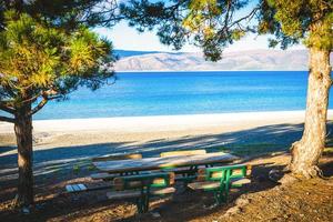 Tranquil view of blue Salda lake in the background and tables surrounded by pine trees in the foreground. Summer holidays and piknik by the lake Turkey photo