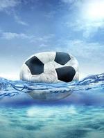 old deflated soccer ball floating in the ocean photo