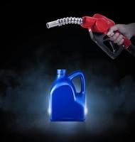 Hands holding Fuel nozzle and blue bottle of engine oil on black background with smoke photo