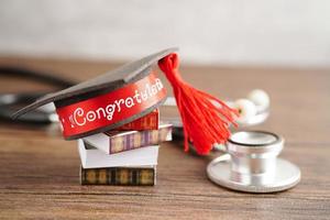 Graduation hat on book and stethoscope with copy space, doctor learning medicine university education concept. photo