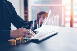 investment financial strategy concept, man holding gold coin and working on keyboard virtual trading graph photo