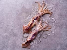 Raw octopus on ice on a black table or board background, fresh octopus for cooked food at a kitchen restaurant or seafood market photo