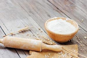 Soft focus, flour in a wooden bowl, ears of wheat, barley, cooking, bread, and cookies arranged on a wooden tabletop in a rustic kitchen, top view. photo