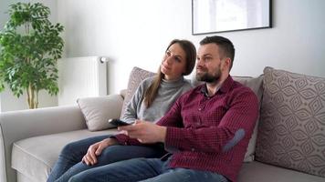 casal do amantes Assistir televisão abraçado em a sofá dentro a Novo casa e Assistir uma filme juntos video