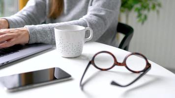 caucasiano mulher tendo café da manhã dentro a cozinha e usando uma computador portátil video