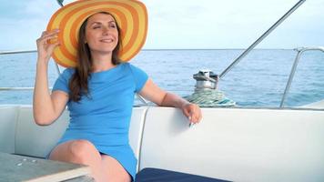 kvinna i en gul hatt och blå klänning flicka vilar ombord en Yacht nära de fyr på sommar säsong på hav video