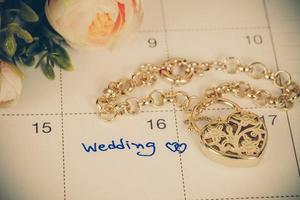 word wedding on calendar and gold bracelet with heart photo