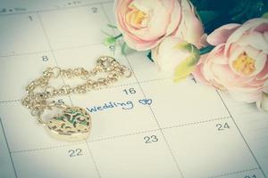 word wedding on calendar and gold bracelet with heart photo